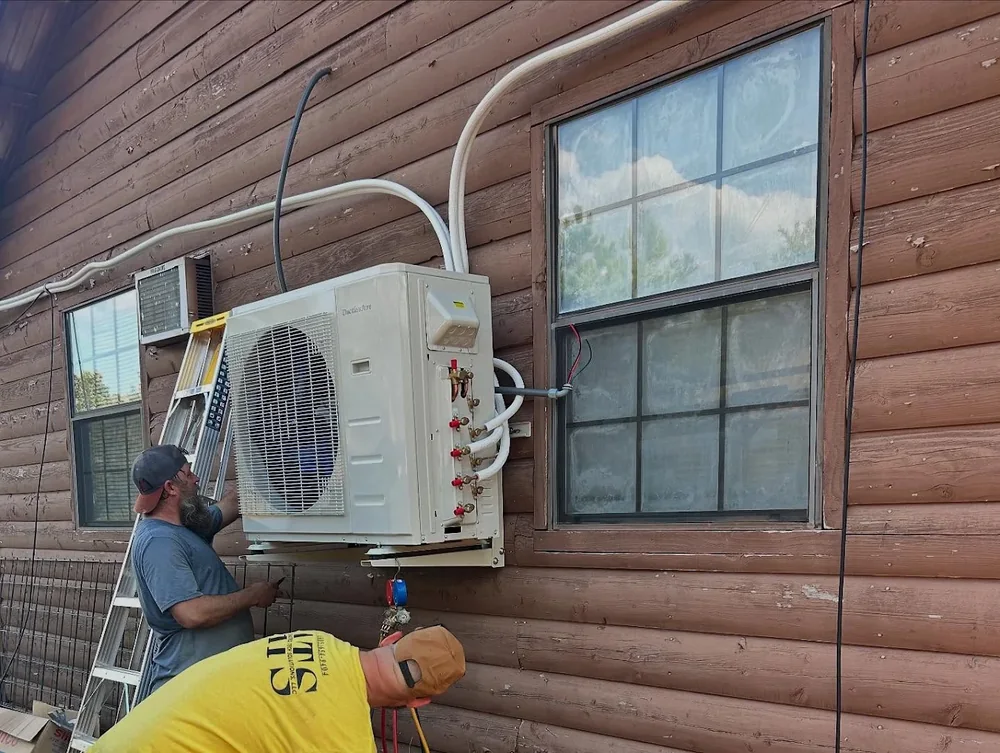 ATS technicians working on a ductless HVAC system at a home